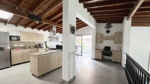 A spacious kitchen with wooden beams, a central island, and a dining area with a view.