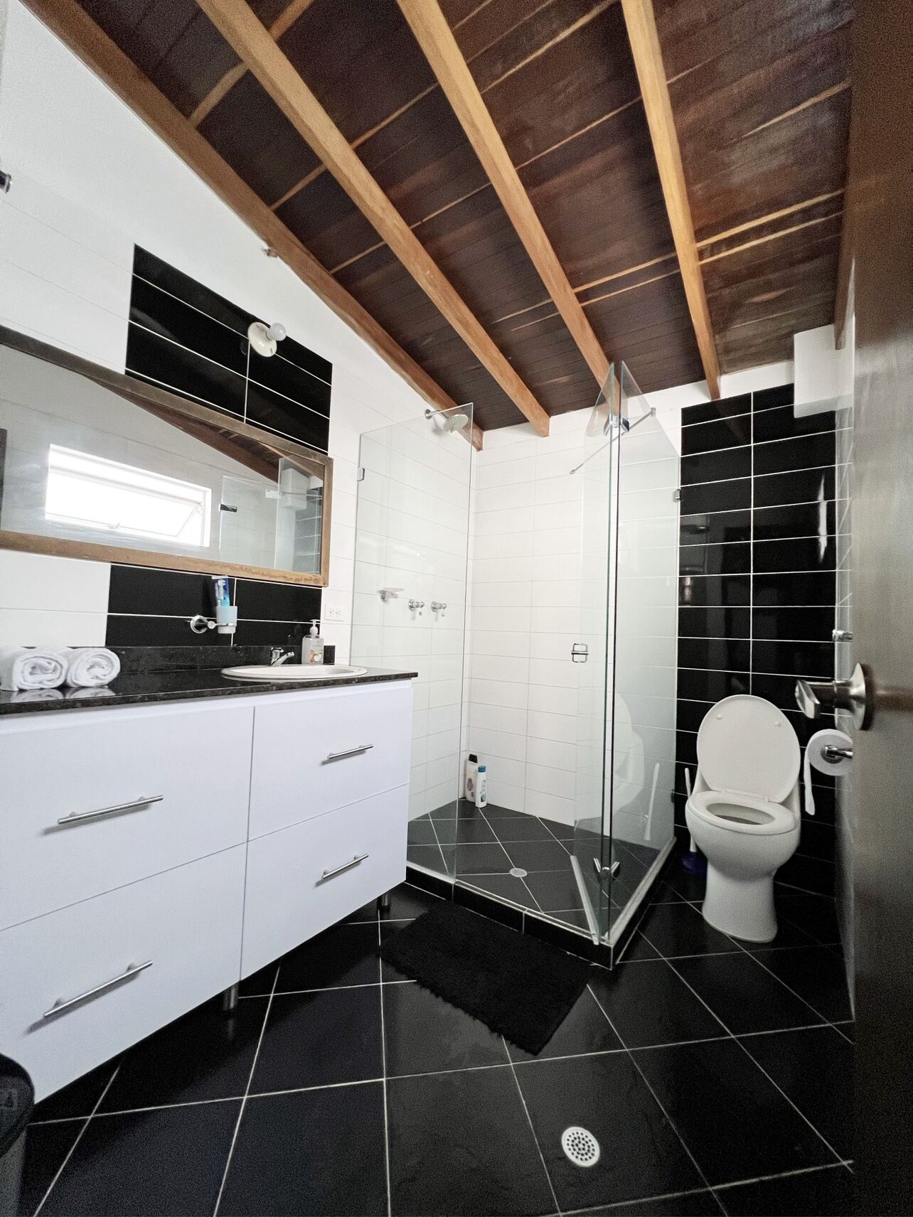 A modern bathroom with a shower, toilet, and white cabinetry.