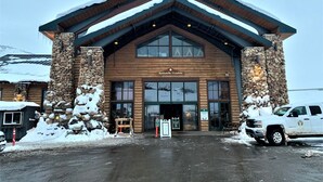 A lodge with a stone facade, large windows, and a wooden roof.