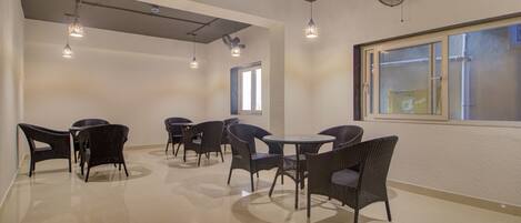 A spacious room with a high ceiling, multiple hanging lights, and a large window providing natural light.