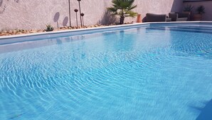 Piscina cristalina con pared texturizada y algunas plantas.