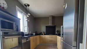 Una cocina moderna con electrodomésticos de acero inoxidable, armarios de madera y piso de baldosas.