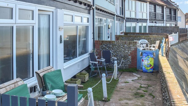 A residential property with a fenced backyard, outdoor seating, and a stone wall. - 1 bedroom accommodation in Sheringham (Sheringham)