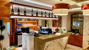 Un espace bar moderne avec un comptoir en marbre, une machine à café et une sélection de bouteilles présentées sur des étagères.