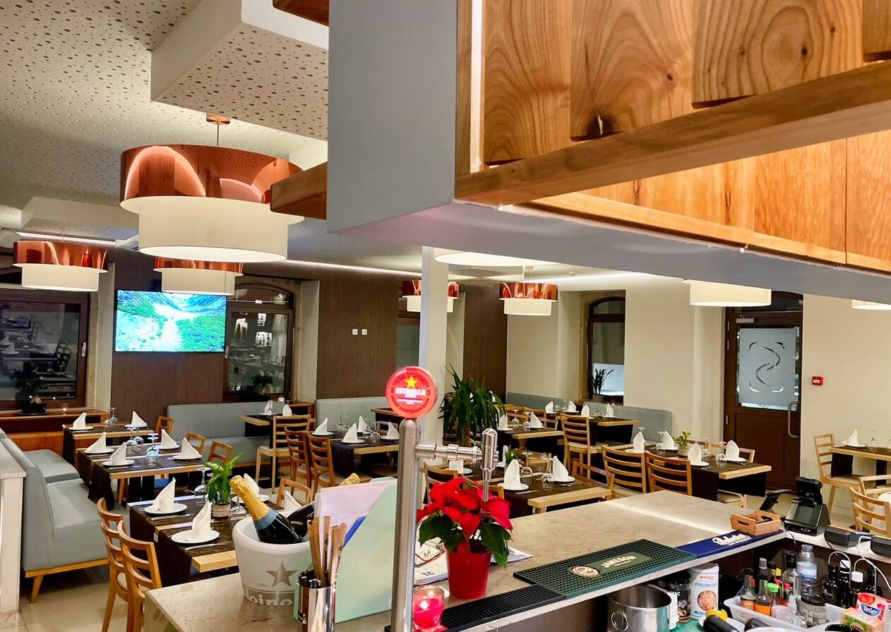 A restaurant with multiple dining tables, chairs, and a bar area.