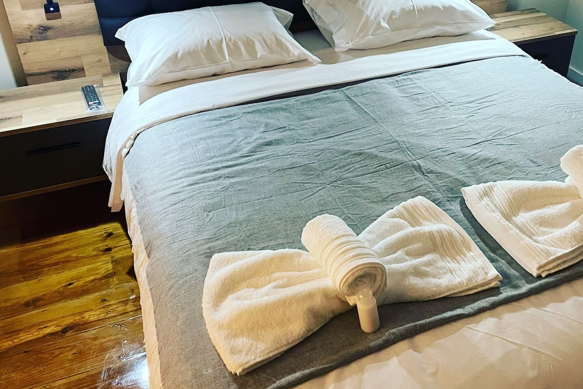 Ein ordentlich gemachtes Bett mit weißen Leinen und auf dem Bett gefalteten Handtüchern.