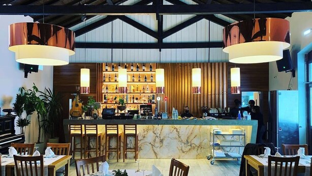 Un restaurant doté d’un bar, de comptoirs en marbre et de chaises en bois.