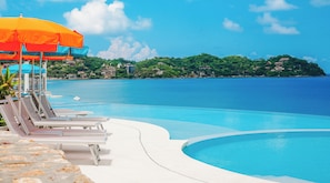 A clear blue pool with lounge chairs and an umbrella, surrounded by a tropical landscape and a view of the sea. - La Puesta (Sayulita)