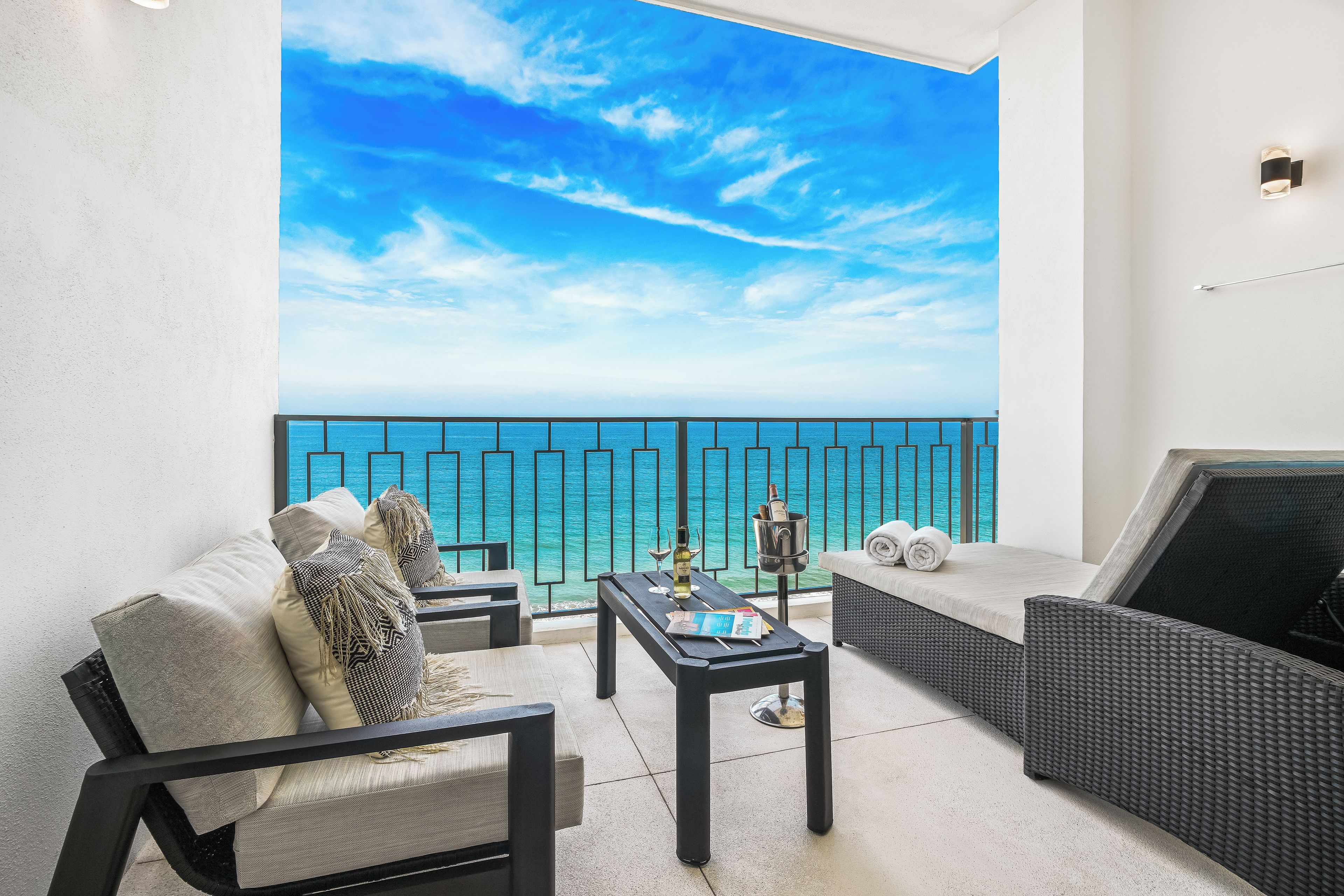 Un balcón con vistas al mar, amueblado con un sofá, una mesa y una silla.