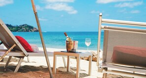 A beachside lounge with a table, a chair, a bottle of champagne, and a glass of wine. - La Puesta (Sayulita)
