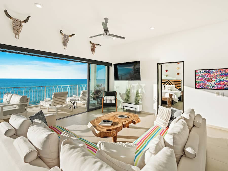 Un soggiorno moderno con vista sul mare, una ventola a soffitto e un televisore a schermo piatto.