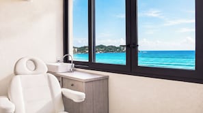 A bathroom with a white bathtub, a sink, and a window with a view of the ocean. - La Puesta (Sayulita)