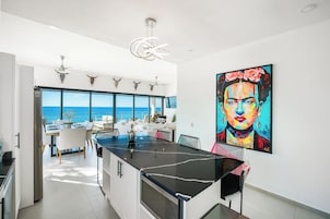 Una cocina moderna con una isla grande, un comedor con vistas y un cuadro de gran tamaño en la pared.