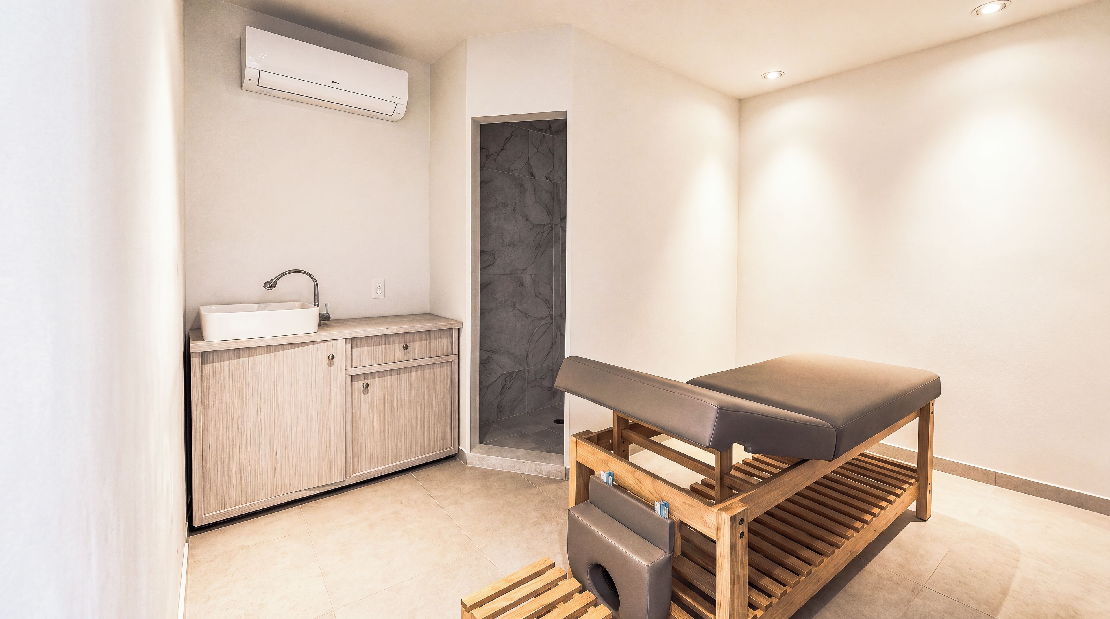 A modern bathroom with a built-in sink, a bench, and a shower area.