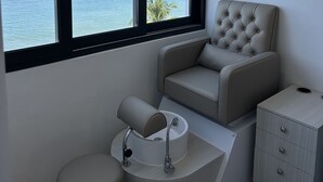 Ein Badezimmer mit Meerblick, einer Toilette, einem Waschbecken und einem Sessel.