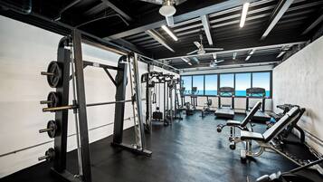 A gym with various exercise equipment, a ceiling fan, and large windows offering a view.