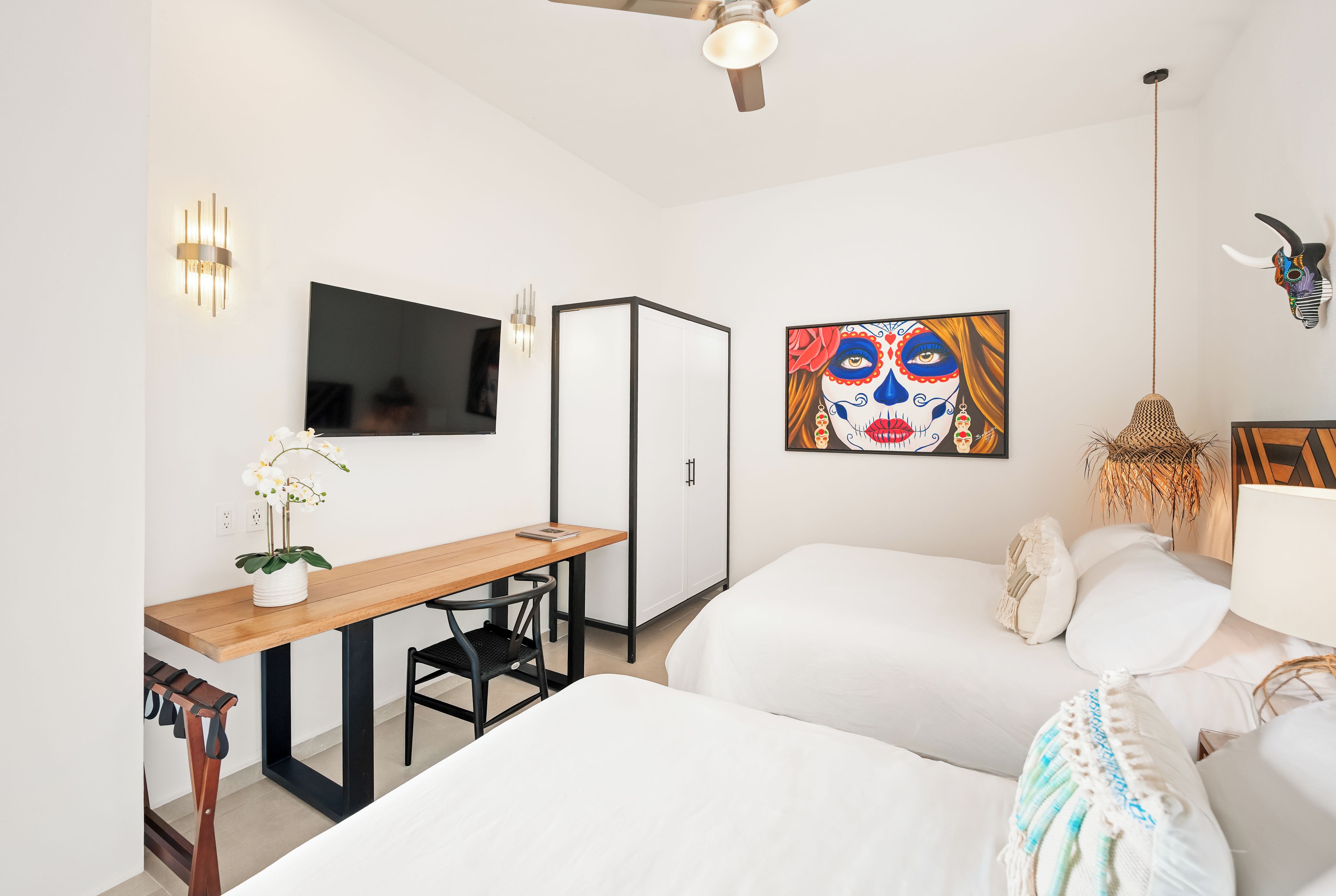 Habitación de hotel moderna con televisión de pantalla plana, escritorio con silla, cama y una obra de arte colgada en la pared.
