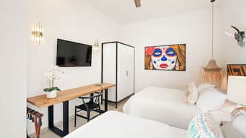 Habitación de hotel moderna con televisión de pantalla plana, escritorio con silla, cama y una obra de arte colgada en la pared.