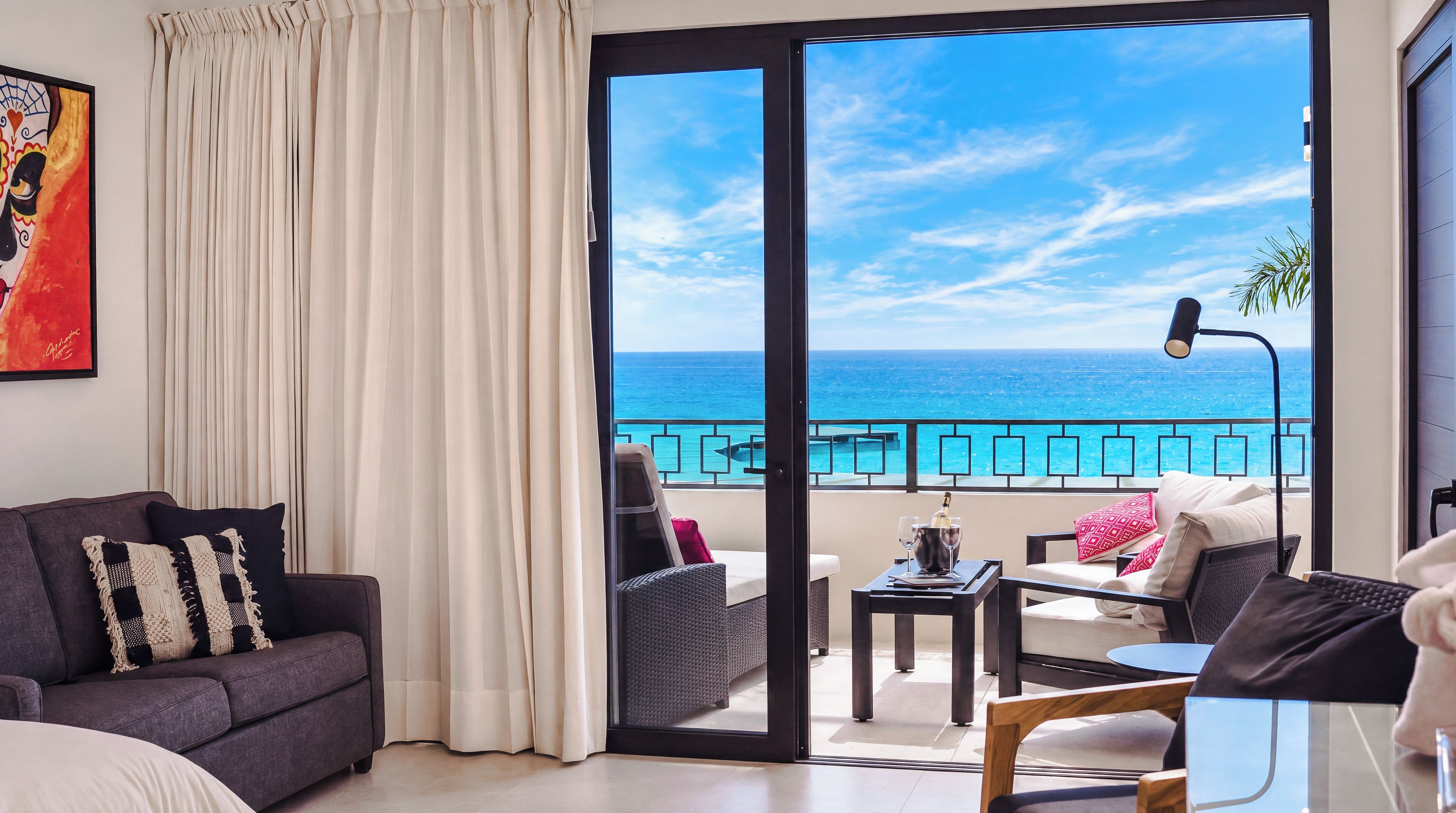 Habitación con balcón que da al mar, amueblada con sofá, sillas y una mesa.