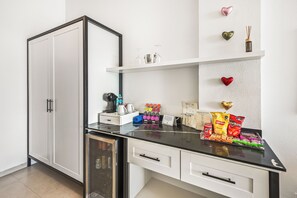 A modern kitchen with a black countertop, white cabinets, and a built-in dishwasher. - La Puesta (Sayulita)