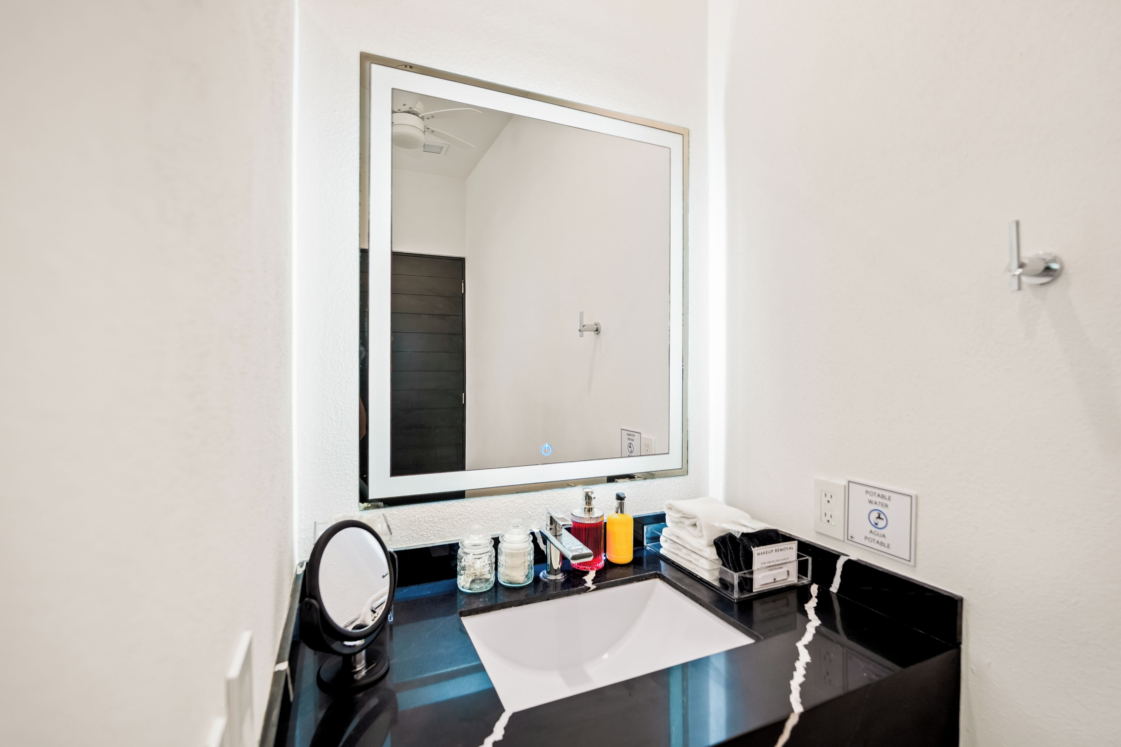 A bathroom with a mirror, sink, and toiletries.