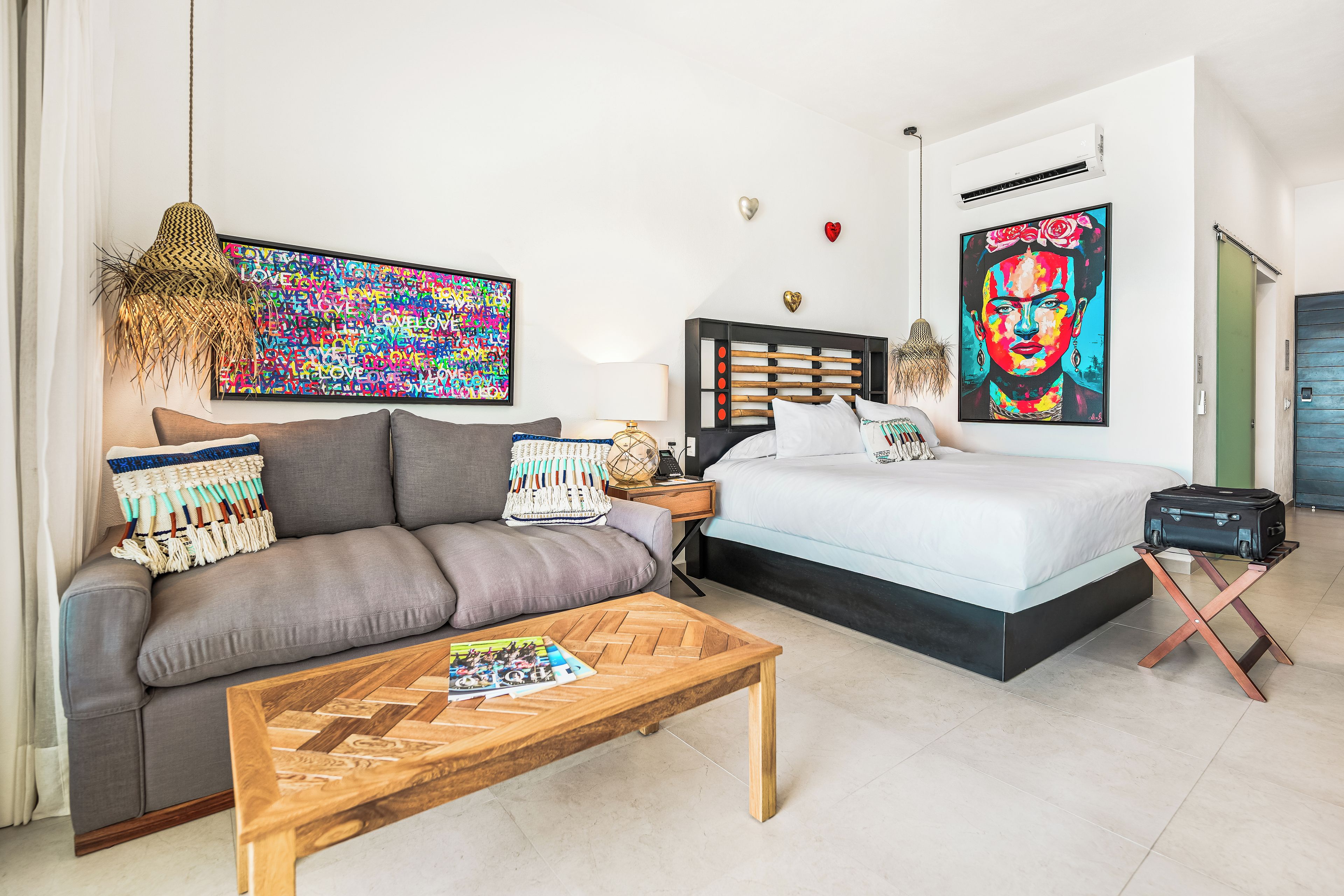 A modern bedroom with a bed, a sofa, a coffee table, and artwork on the walls.