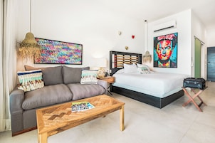 Un dormitorio moderno con una cama, un sofá, una mesa de centro y obras de arte en las paredes.