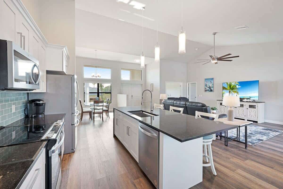 A modern kitchen with a central island, stainless steel appliances, and a dining area with a sofa and table.