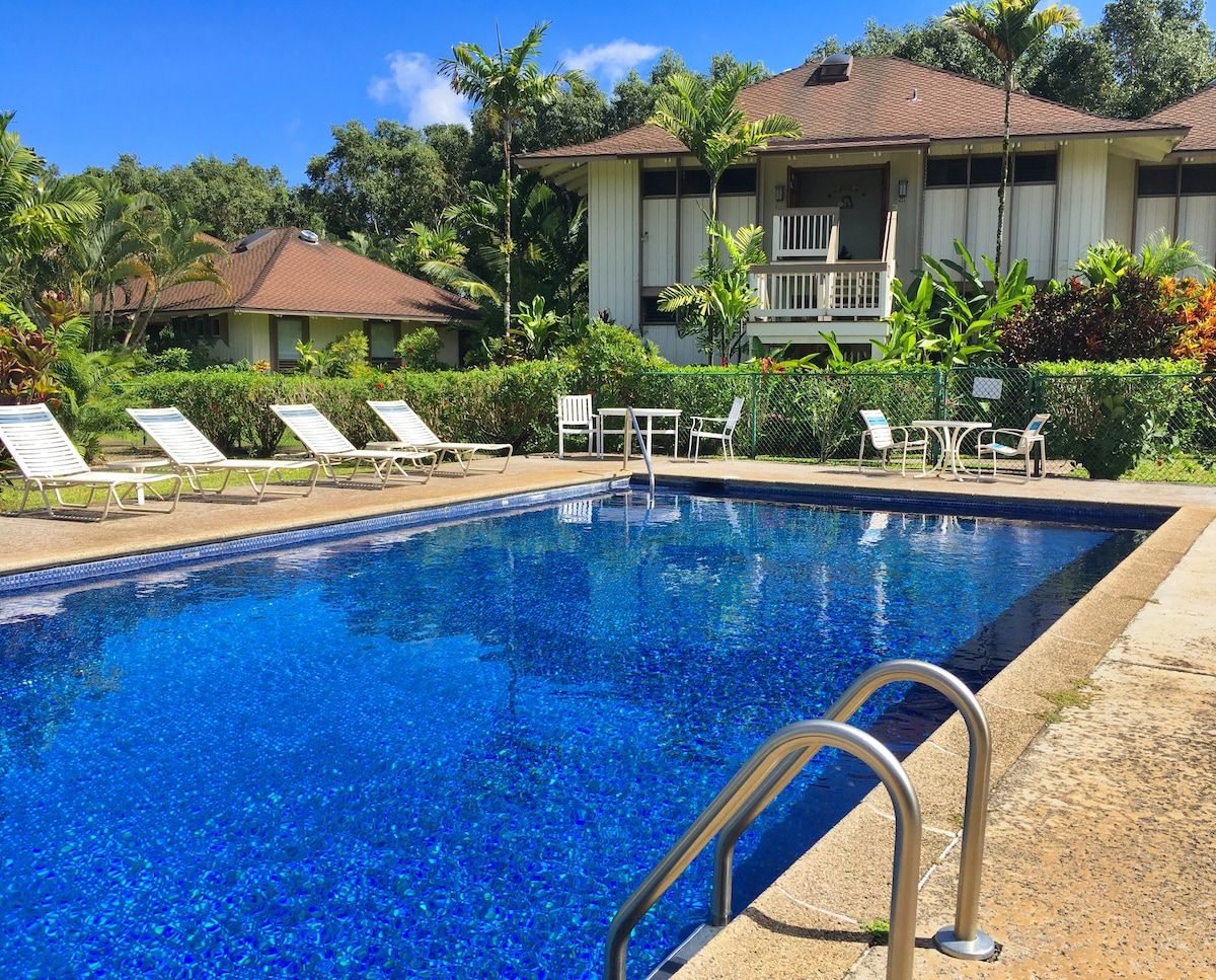 A swimming pool with lounge chairs and a building in the background.