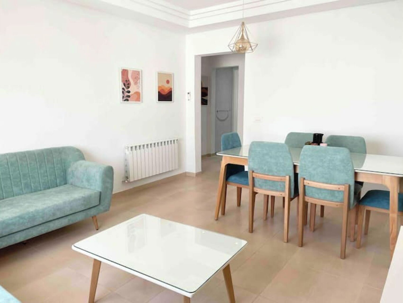 Ein modernes Wohnzimmer mit einer Couch, einem Glastisch und einem Essbereich mit Stühlen und einem Tisch.