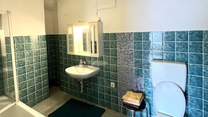 A bathroom with a bathtub, sink, and toilet. - Ferienwohnung Göss (Leoben)