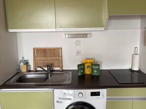 A kitchen with a washing machine, a wooden rack, and a welcome kit. - Comfortable 40 m² apartment with sea view (Sainte-Maxime)