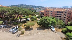 A residential area with apartment buildings, a parking lot, and a hilly landscape in the background.