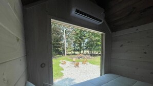 Ein Schlafzimmer mit großem Fenster, einem Bett und einer Klimaanlage.