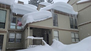 Un edificio de dos plantas con techos nevados y un porche delantero.