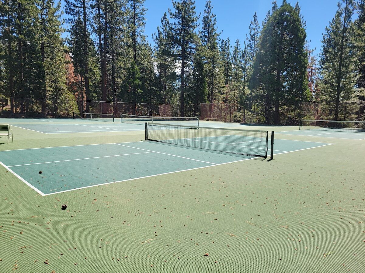 Un court de tennis en plein air, entouré de grands arbres.