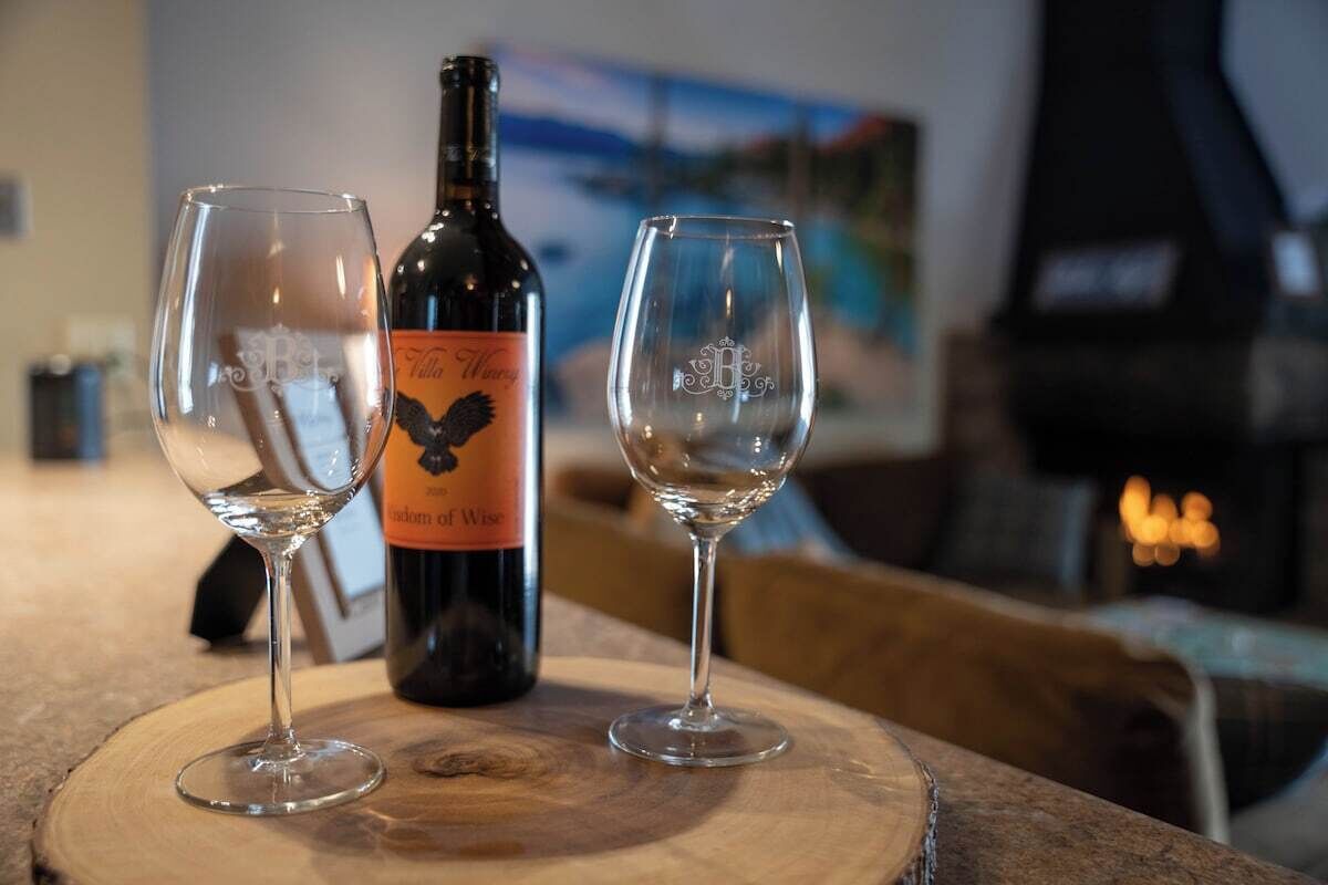 A bottle of wine and two empty wine glasses on a wooden table.