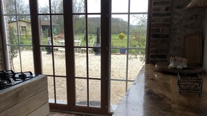 A kitchen with a wooden countertop, a gas stove, and a sliding glass door leading to an outdoor patio with a garden view. - Une Longere de la Puisaye en Fond Dimpasse Avec Parc Apaisant (La Ferté-Loupière)