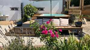 A poolside seating area with a wooden deck, a large umbrella, and a view of a swimming pool. - Une Longere de la Puisaye en Fond Dimpasse Avec Parc Apaisant (La Ferté-Loupière)
