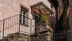 A stone archway leading to a balcony with a metal railing, a stone wall, and a gate. - Carosa - Luxusberghaus mit Seeblick (Peglio)