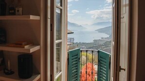 A room with a view of a lake and mountains through open shutters. - Carosa - Luxusberghaus mit Seeblick (Peglio)