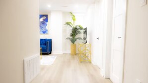 A hallway with a blue sofa, a potted plant, and a yellow decorative stand.