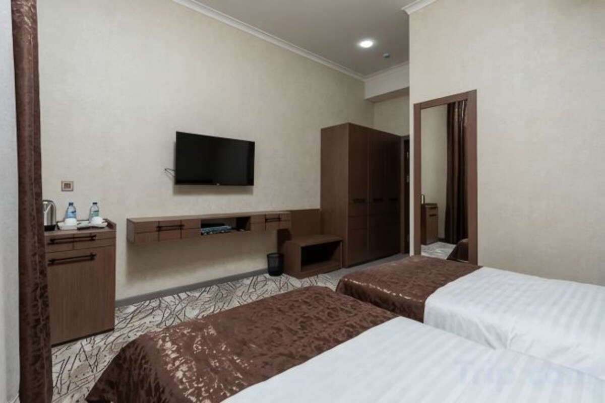A hotel room with two beds, a TV, a desk, and a wardrobe.