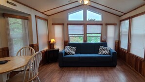 A cozy room with a wooden floor, a blue sofa with patterned cushions, a small table with chairs, and a lamp. - The Lakeview at Northside Marina & Resort (chico)