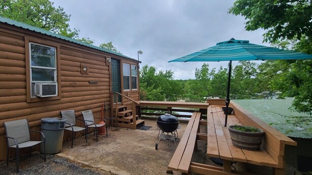A wooden cabin with a patio area featuring outdoor seating, a barbecue grill, and a covered table. - The Lakeview at Northside Marina & Resort (chico)