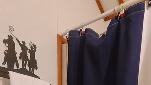 Une salle de bain avec des toilettes blanches, une serviette suspendue à un porte-serviettes et un rideau de douche orné de motifs en forme d’étoile.
