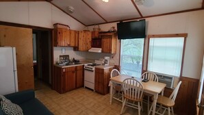 Une cuisine de taille réduite, dotée de meubles en bois, d’une cuisinière et d’une table à manger avec des chaises.