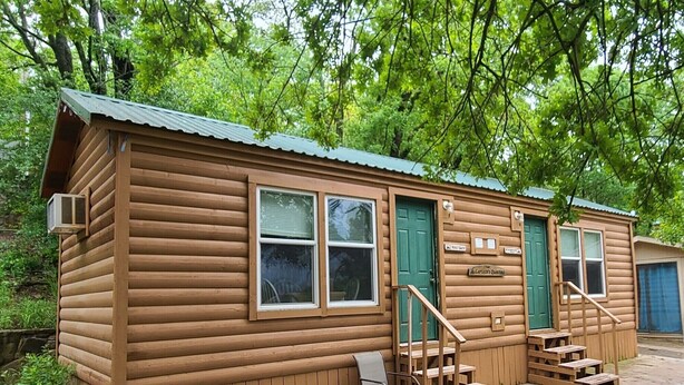 A wooden cabin with two green doors, a small porch with a chair, and a sign that reads "The Cartwright's Quarters." - The Captains Quarters at Northside Marina & Resort (chico)