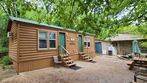 A wooden cabin with a porch, a small staircase, and a patio area with a table and chairs. - The Captains Quarters at Northside Marina & Resort (chico)