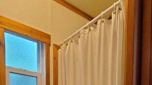 A bathroom with a bathtub, a window, and a toilet. - The Captains Quarters at Northside Marina & Resort (chico)